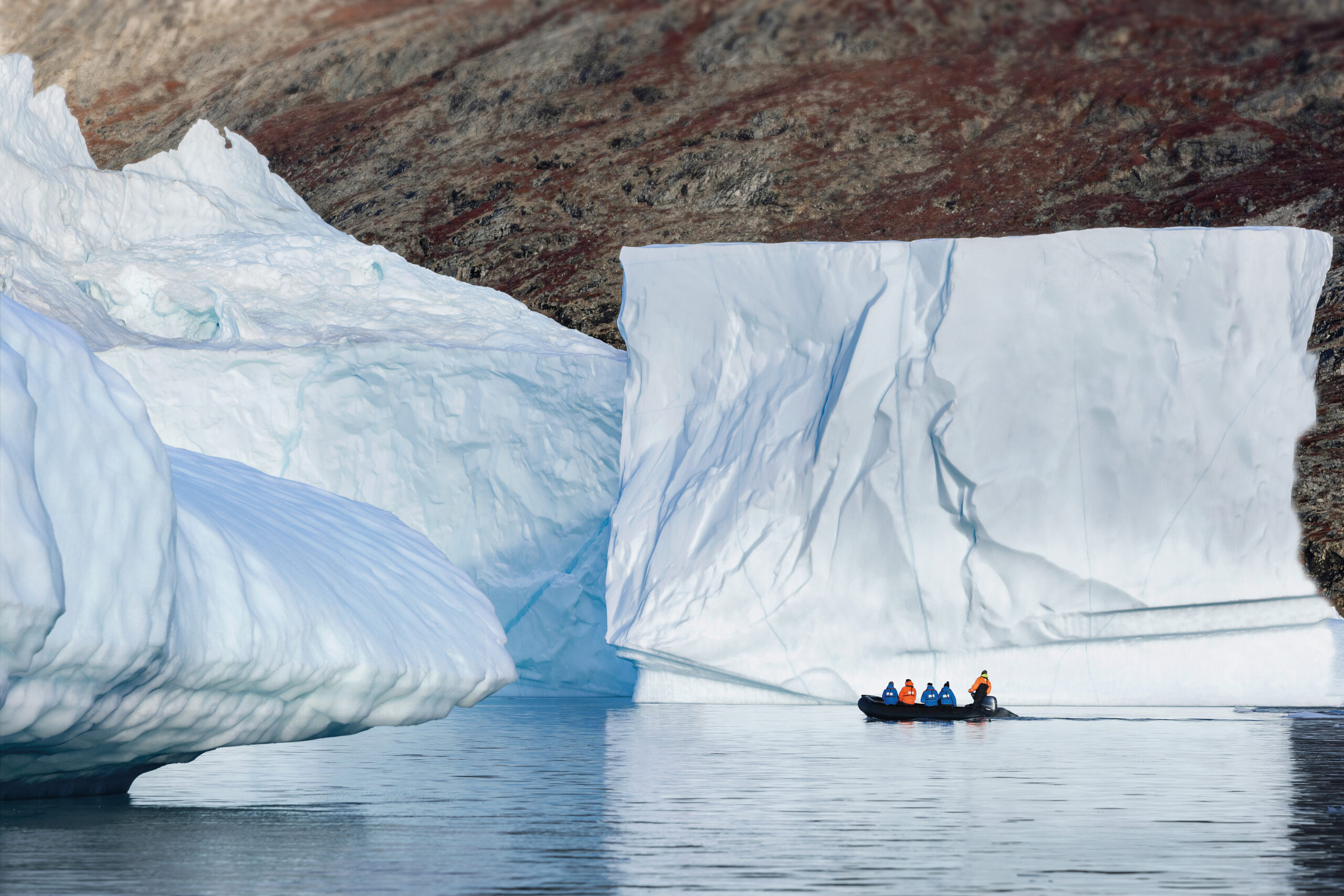 Zodiac vaart tussen ijsbergen in Antarctica met besneeuwde bergen op de achtergrond